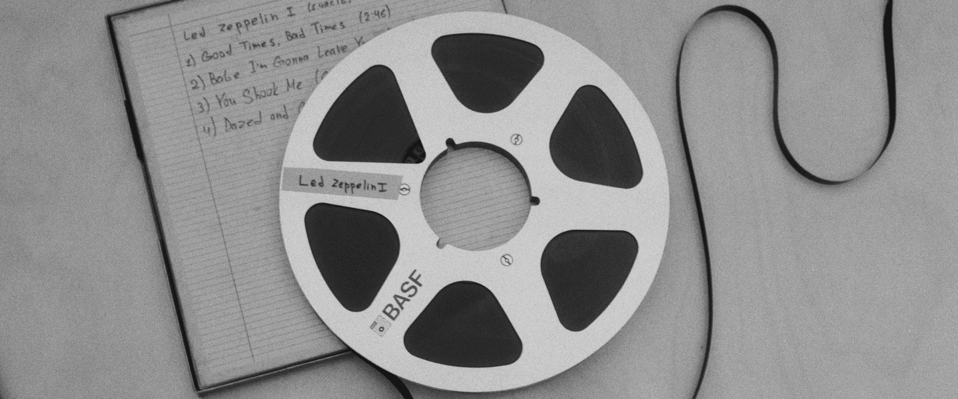 Led Zeppelin music reel on a desk with a notebook and computer mouse, vintage style.