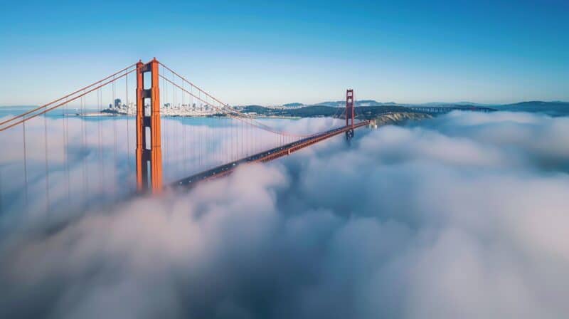 Golden Gate Bridge shrouded in fog, iconic San Francisco landmark, breathtaking aerial view, city skyline in background, California scenery.